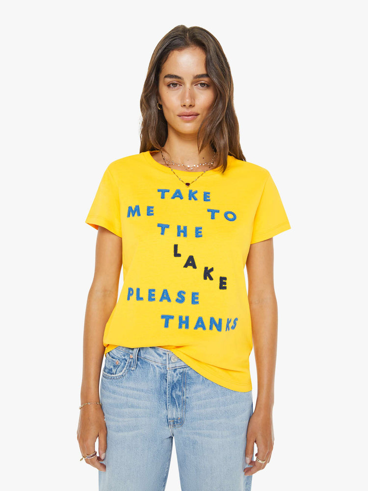 Front view of a woman in a  yellow tee with a blue text graphic on the front.