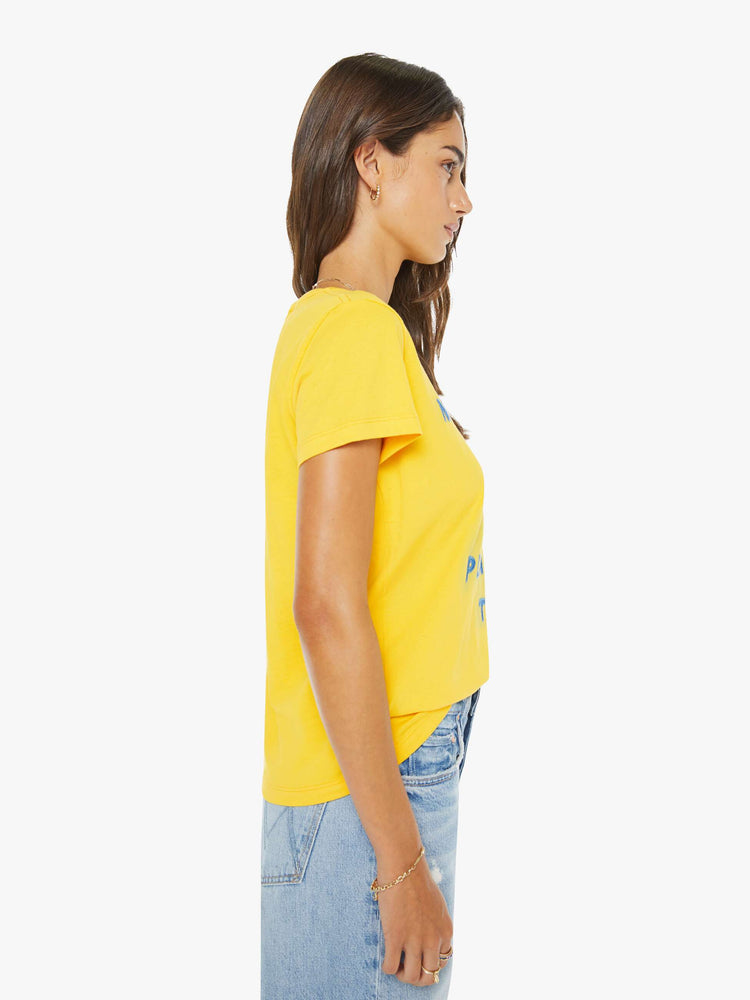 Side view of a woman in a  yellow tee with a blue text graphic on the front.