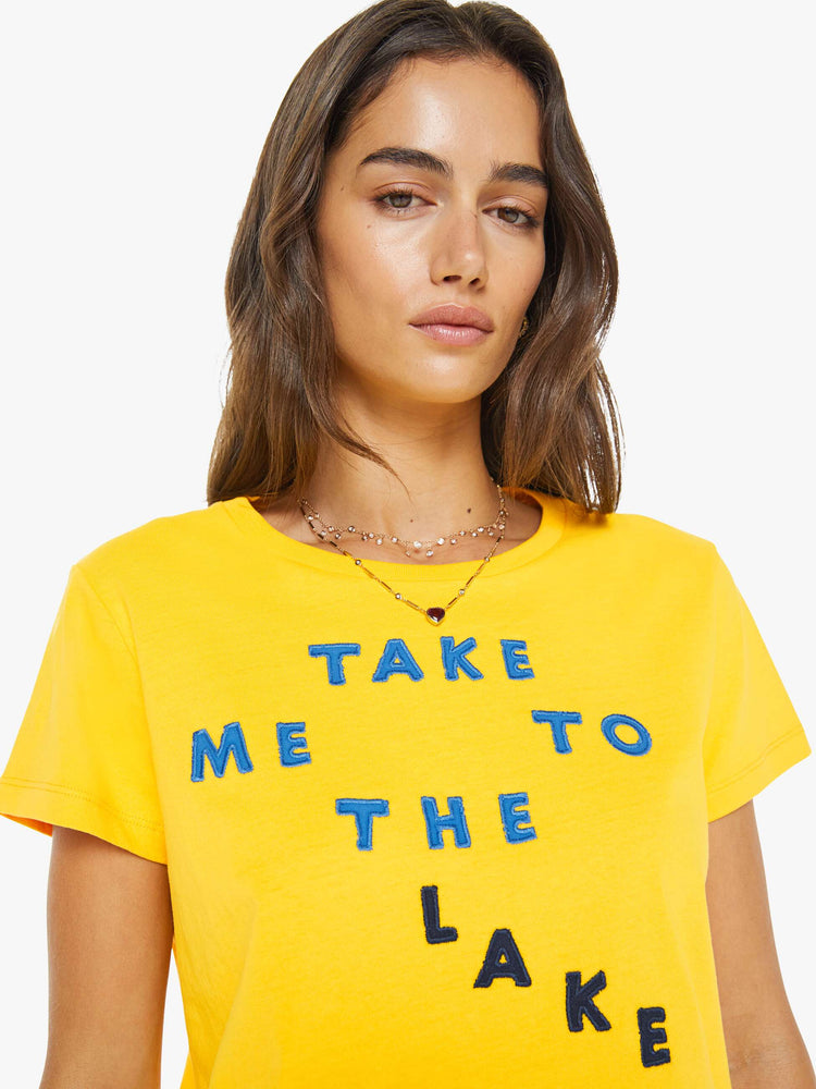 Close up view of a woman in a  yellow tee with a blue text graphic on the front.