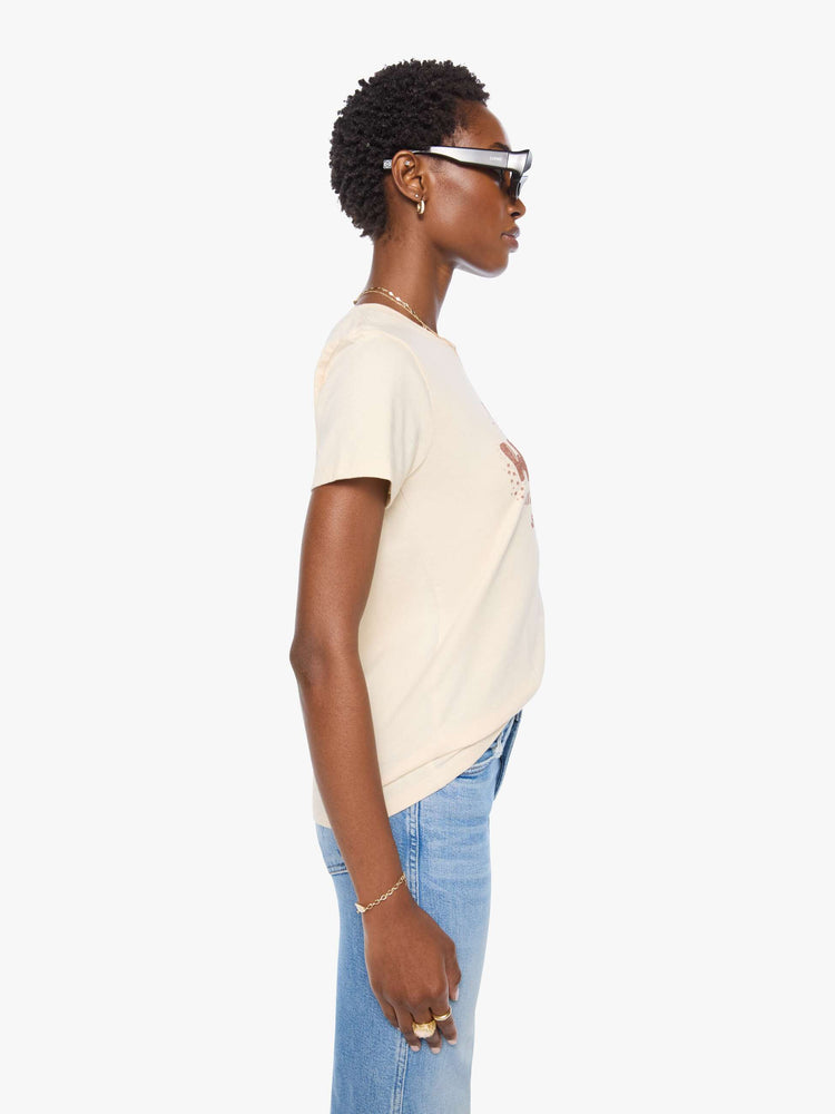 Side view of a woman in a cream tee with a vintage-inspired Western graphic across the chest.