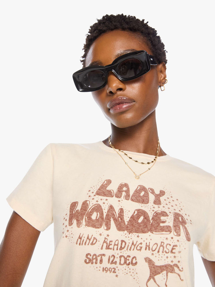 Close up view of a woman in a cream tee with a vintage-inspired Western graphic across the chest.