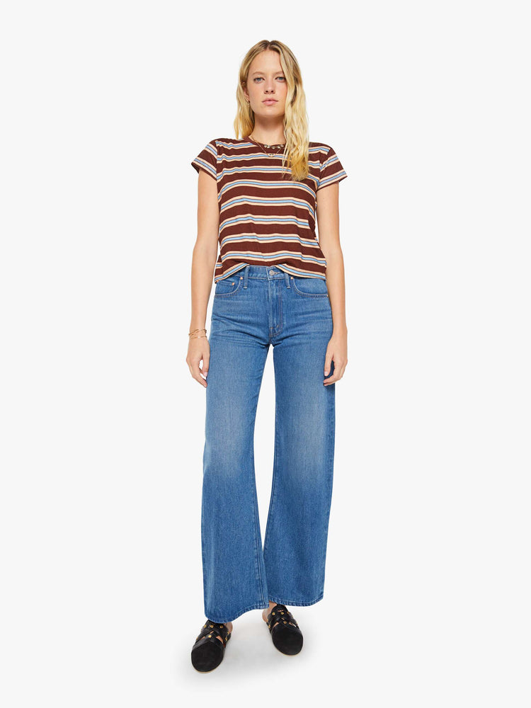 Full body view of a woman in a brown tee with printed horizontal stripes in cream and light blue.
