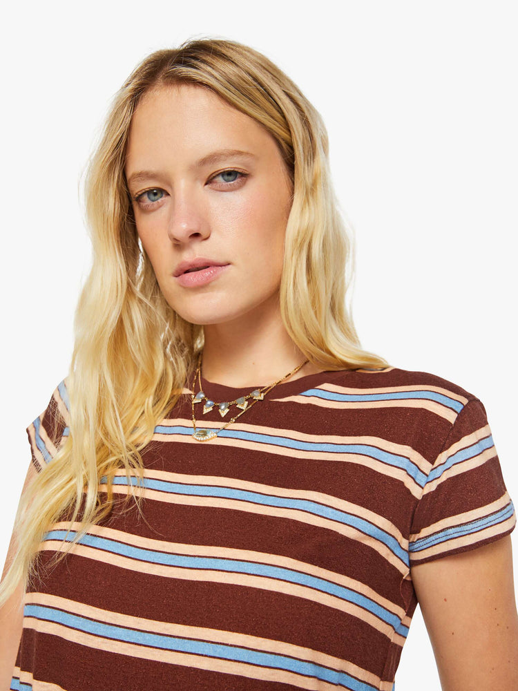 Close up view of a woman in a brown tee with printed horizontal stripes in cream and light blue.