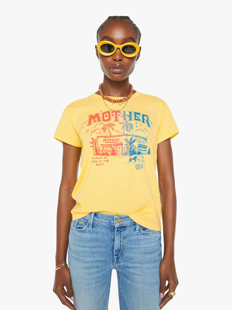 Front view of a woman in a yellow crewneck tee with a tropical storefront graphic in red and blue on the front.