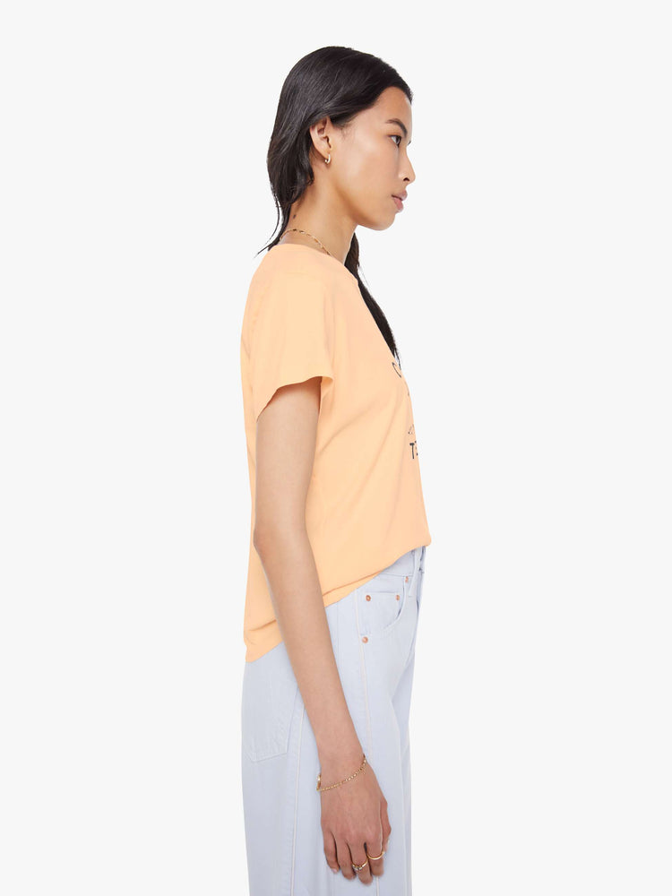 Side view of a woman in light peach, the tee features a black dog graphic with text on the front.