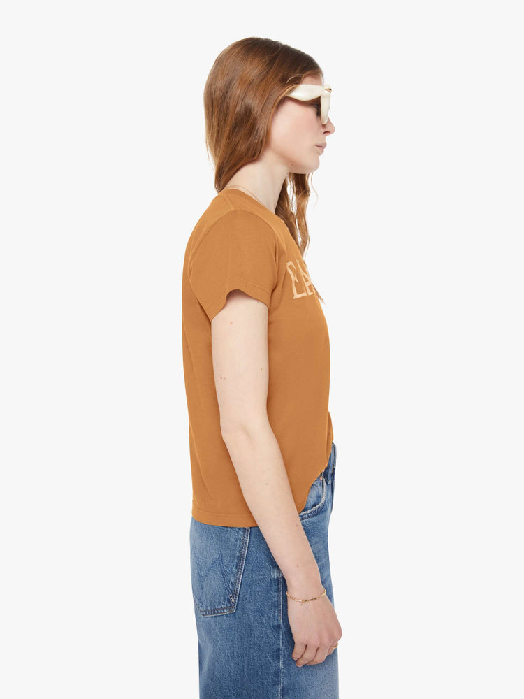 Side view of a woman in a dark khaki tee with cream writing.