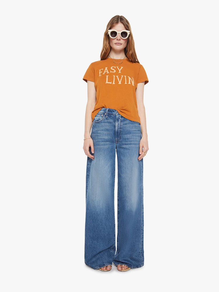 Full body view of a woman in a dark khaki tee with cream writing.