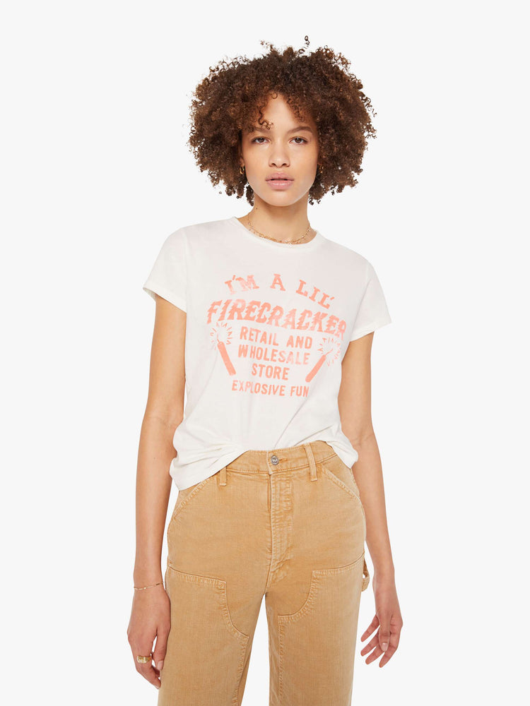 Front view of a woman in white with a faded peach text graphic on the front crewneck tee.