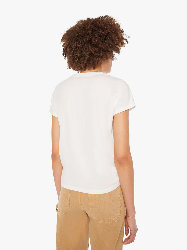Back view of a woman in white with a faded peach text graphic on the front crewneck tee.