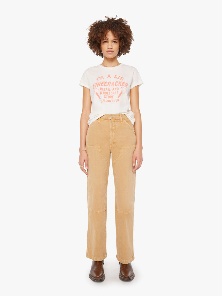 Full body view of a woman in white with a faded peach text graphic on the front crewneck tee.