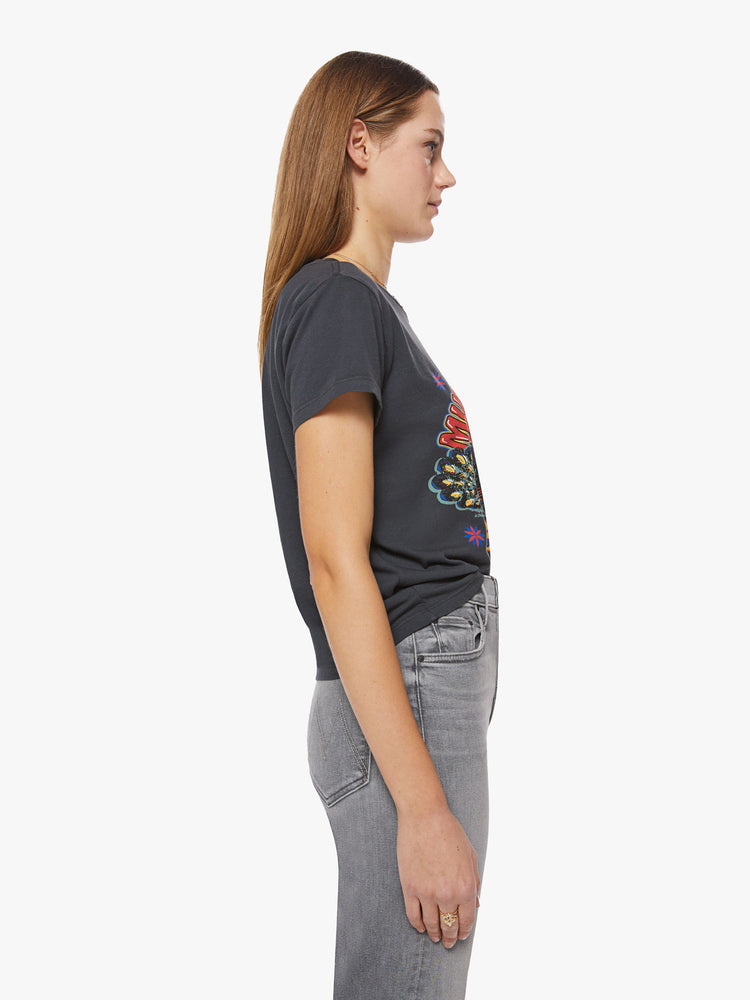 Side view of a woman faded black soft crewneck with a colorful graphic with peacocks and text on the front.