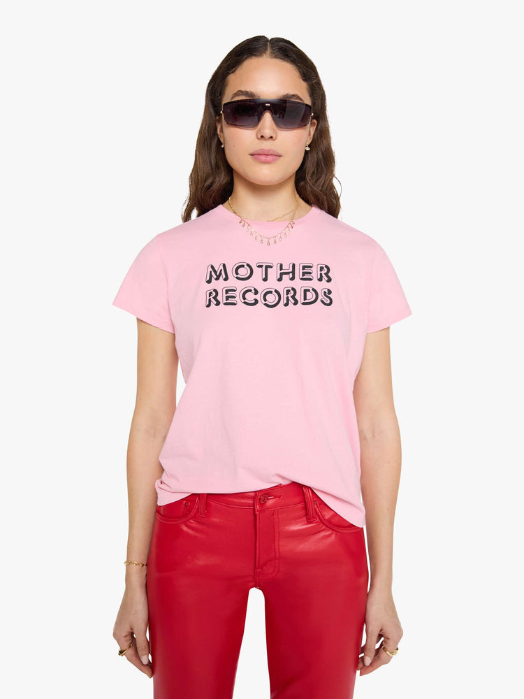 Front view of a woman in a baby pink tee with a text graphic in black across the front.
