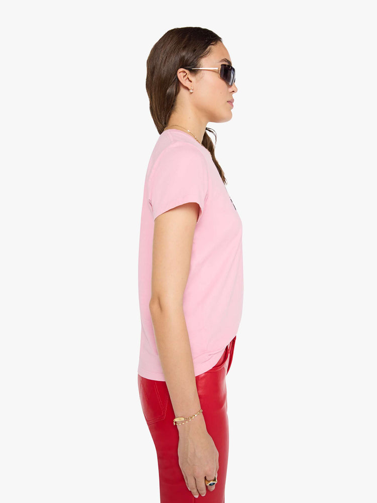 Side view of a woman in a baby pink tee with a text graphic in black across the front.