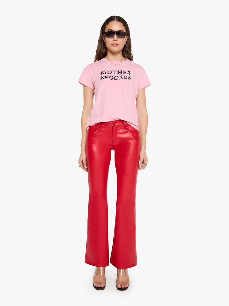 Full body view of a woman in a baby pink tee with a text graphic in black across the front.