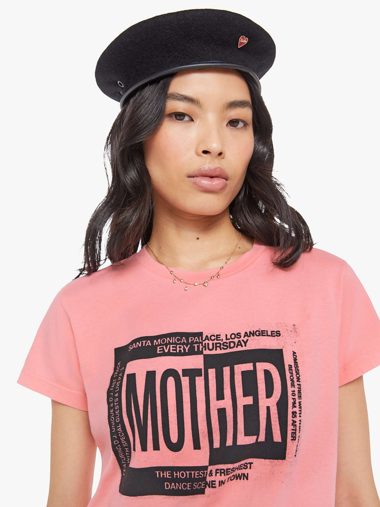 Close up view of a woman in a light pink  tee with a ticket-inspired graphic and MOTHER's name in black on the front.