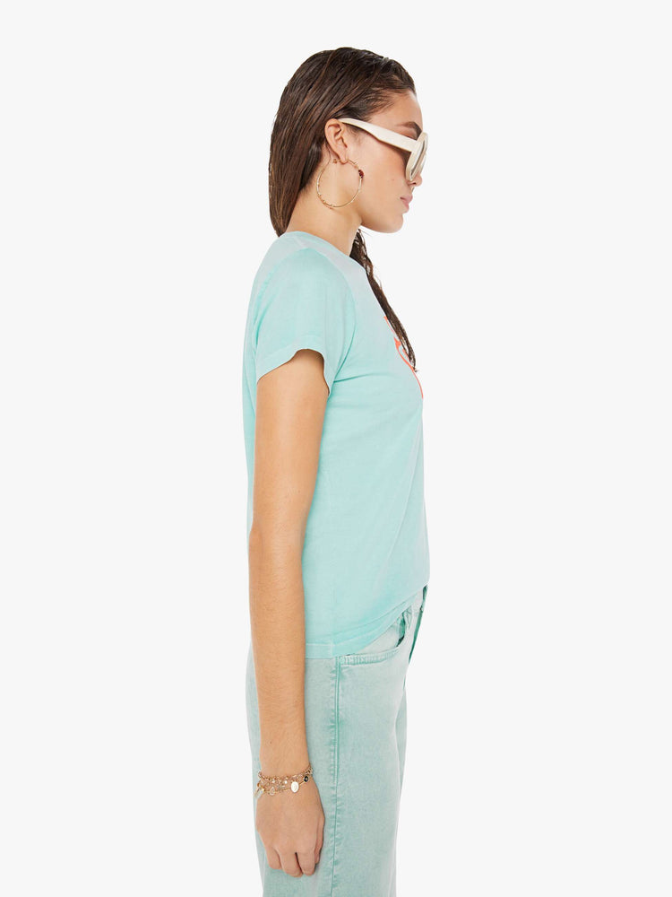 Side view of a woman wearing a light teal, fitted crew neck tee, paired with a light teal pant.