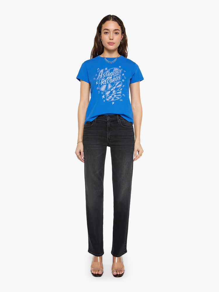 Full body view of a woman in a primary blue tee is designed with a glittery silver graphic inspired by a vintage record store.