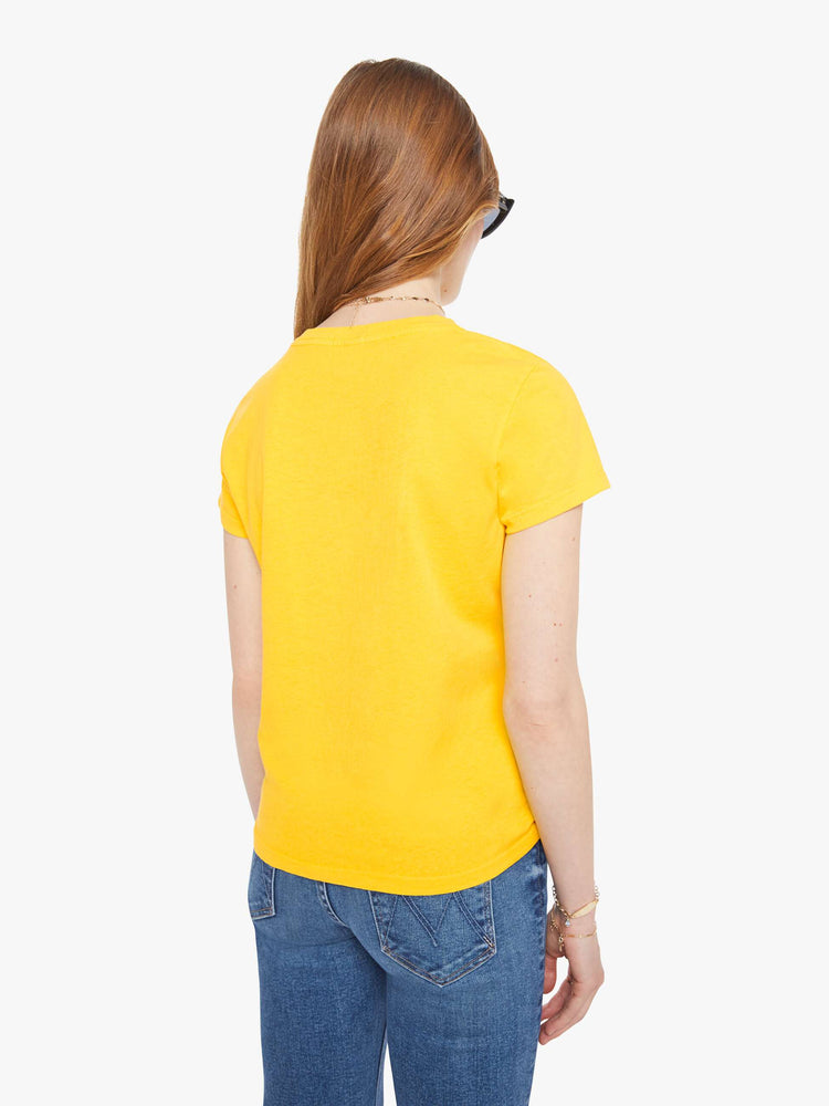 Back view of a woman in bright yellow, the tee features a bike show graphic in tan on the front.