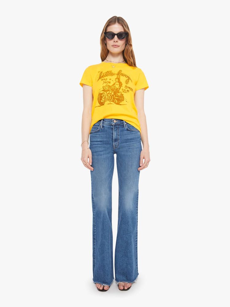 Full body view of a woman in bright yellow, the tee features a bike show graphic in tan on the front.