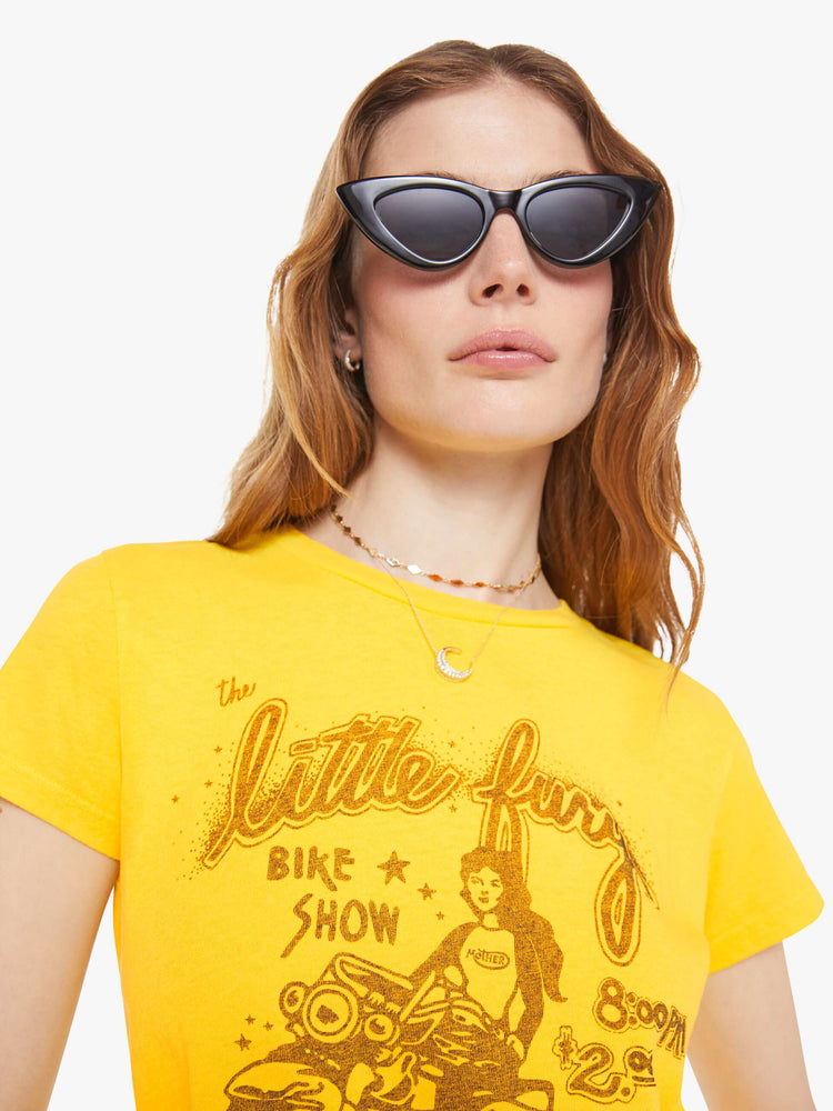 Close up view of a woman in bright yellow, the tee features a bike show graphic in tan on the front.