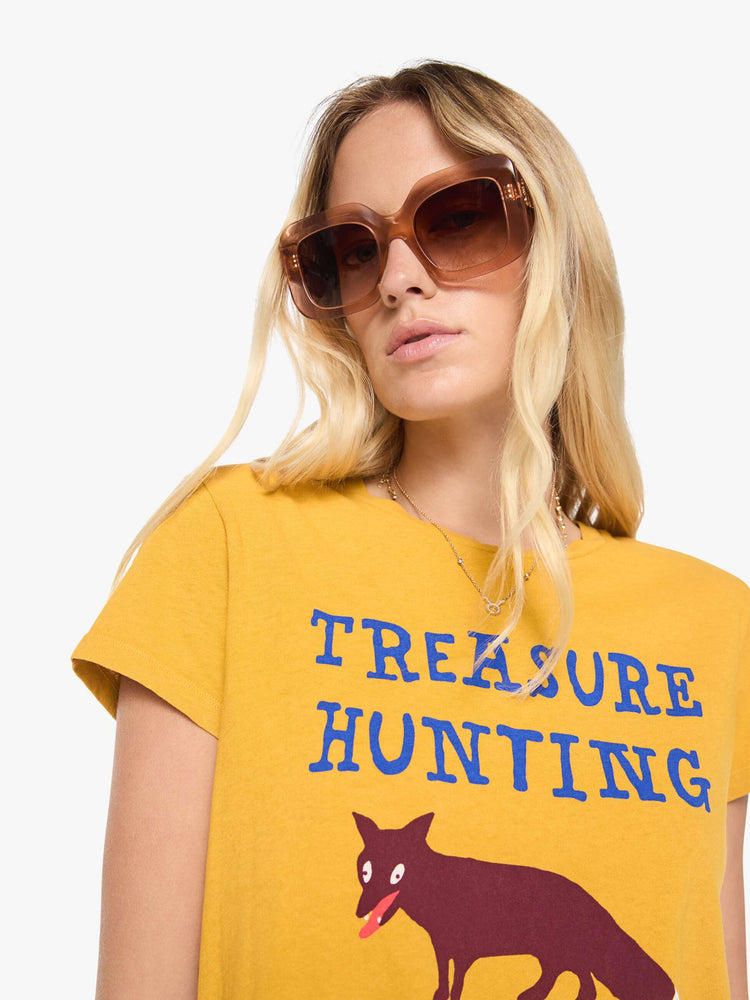 Close up view of a woman in a golden yellow  tee features a colorful fox graphic and text in blue across the front.
