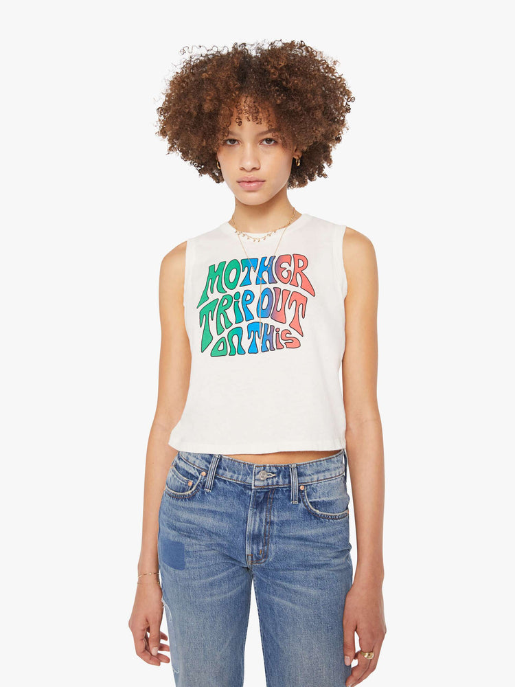 Front view of a woman in a cropped muscle tee in white with a trippy text graphic on the front.