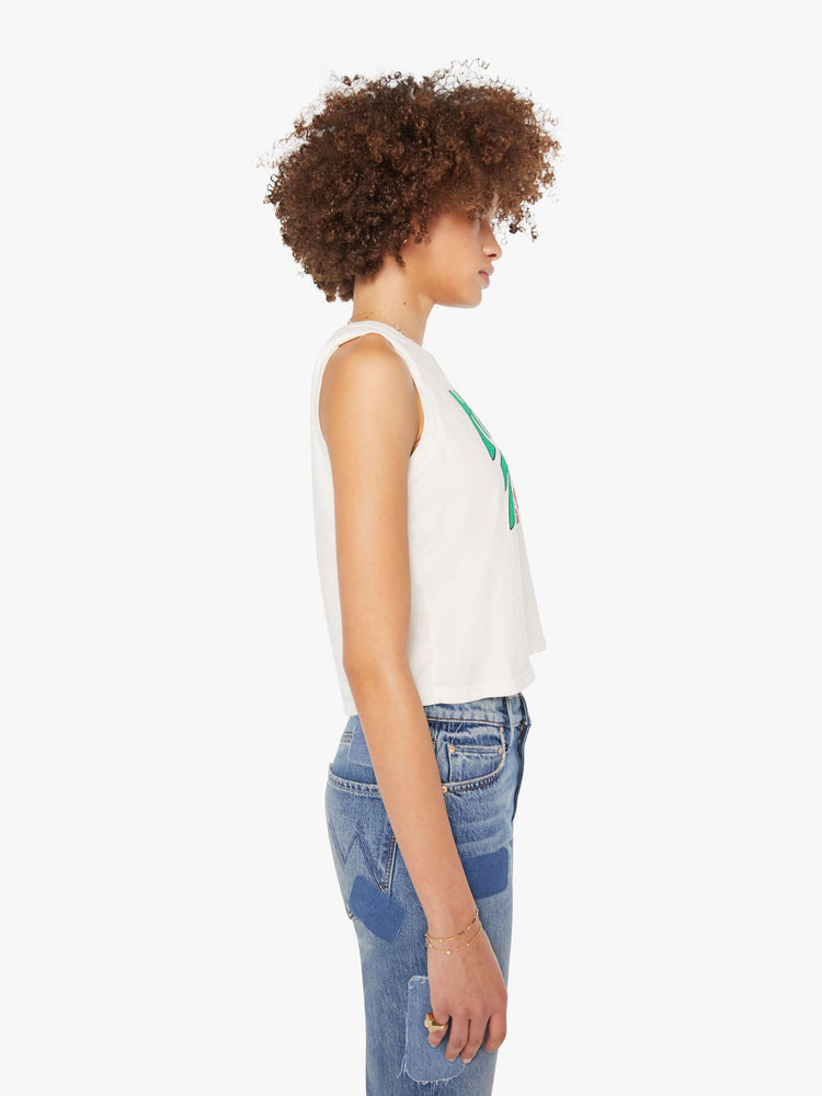 Side view of a woman in a cropped muscle tee in white with a trippy text graphic on the front.