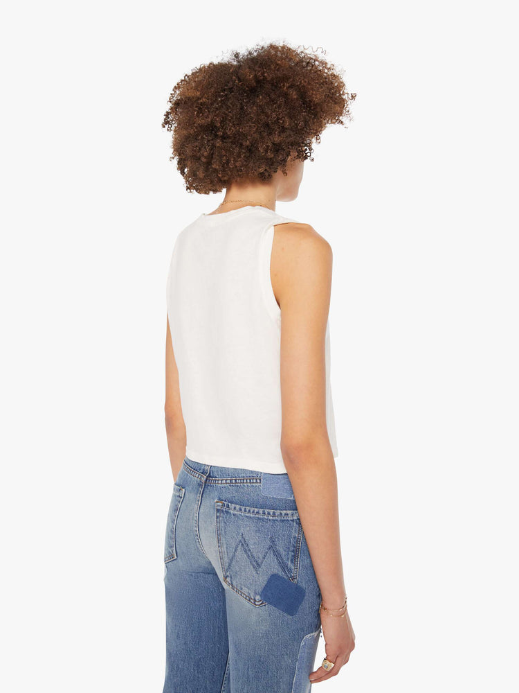 Back view of a woman in a cropped muscle tee in white with a trippy text graphic on the front.