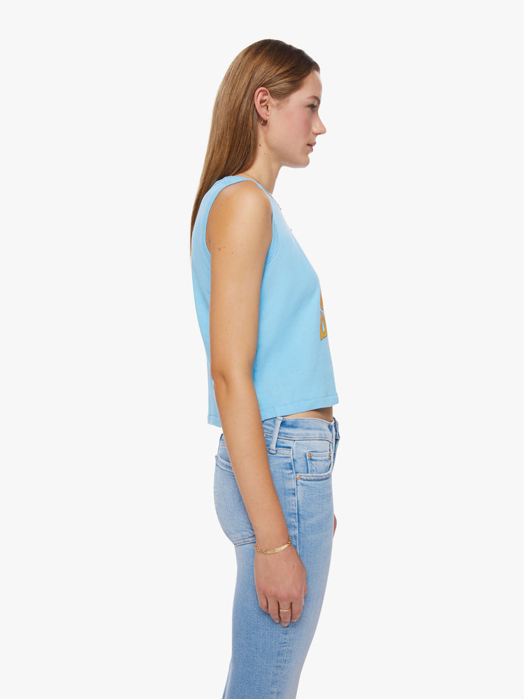 Side view of a woman cropped muscle tee with a crewneck and boxy fit in baby-blue tank with a text graphic in a warm gradient hues.