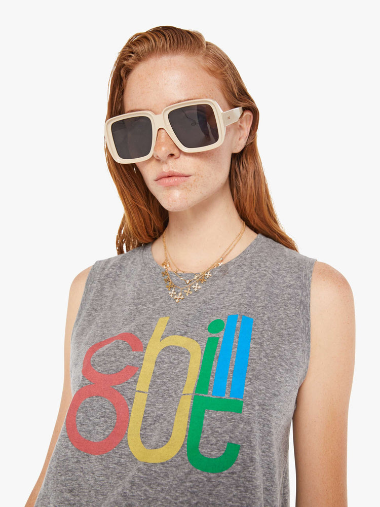 A front close up view of a woman wearing a heather grey crew neck tank featuring a colorful graphic reading "chill out".