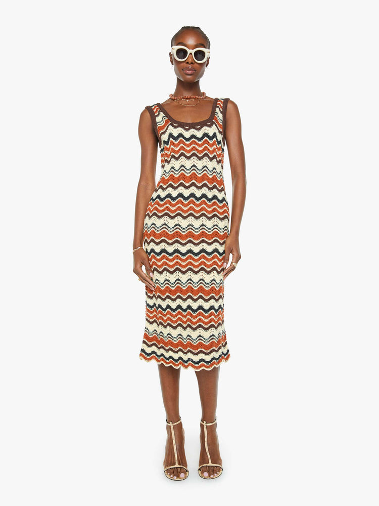 Front view of a woman in a striped graphic print sleeveless midi dress with a scoop neck, narrow fit and scalloped hem that hits at the calf.