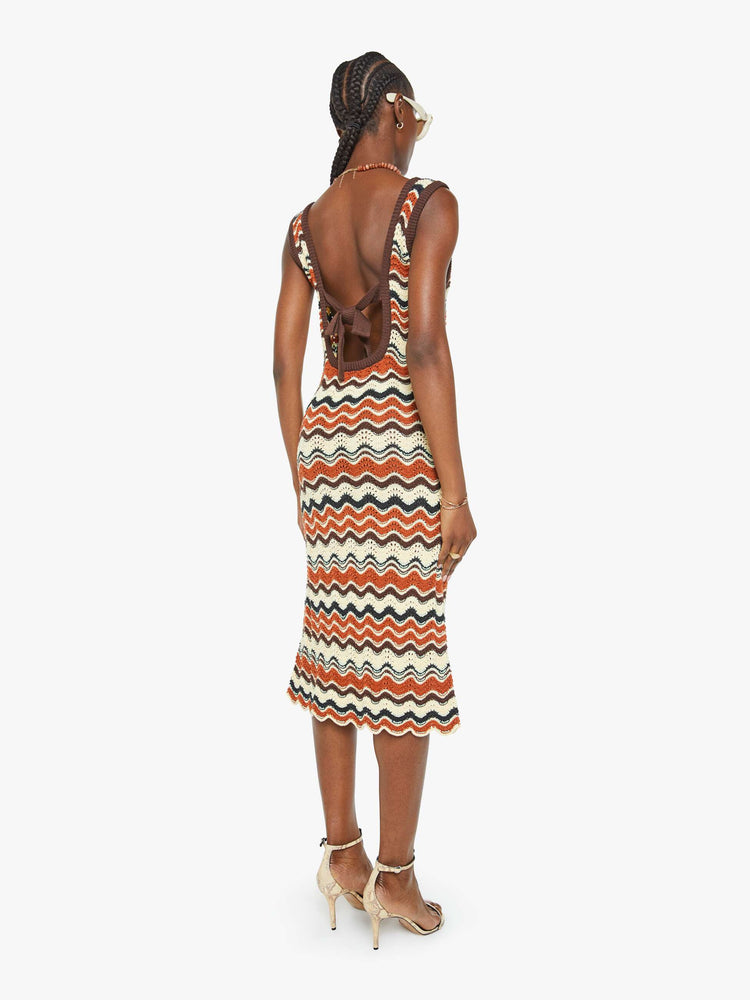Back view of a woman in a striped graphic print sleeveless midi dress with a scoop neck, narrow fit and scalloped hem that hits at the calf.