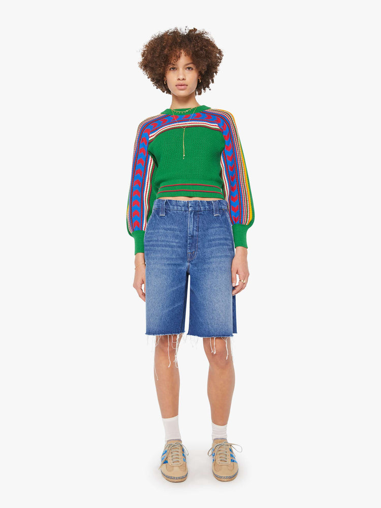 Full body view of a woman in a green sweater with balloon sleeves, ribbed hems and a cropped fit.