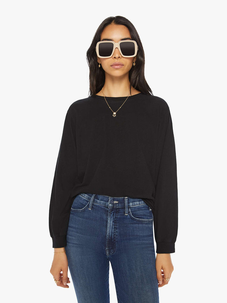 Front view of a woman black crewneck tee with long sleeves and an oversized fit.