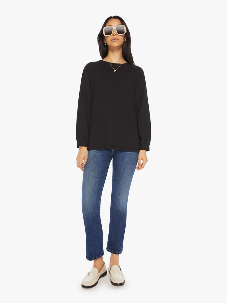 Full body view of a woman black crewneck tee with long sleeves and an oversized fit.