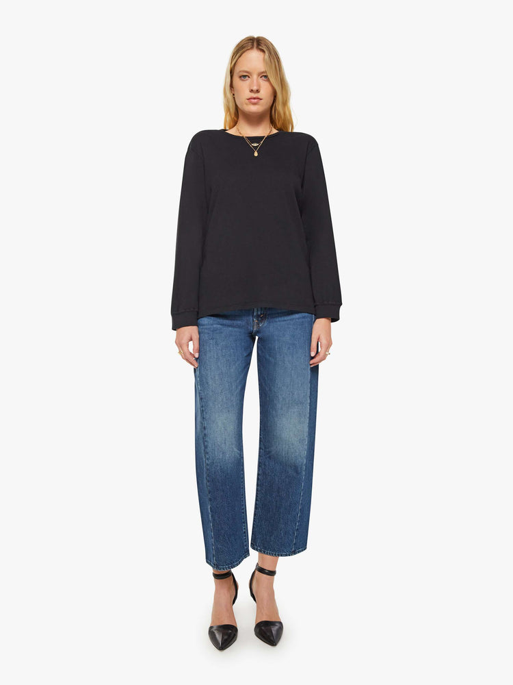 Full body view of a woman black crewneck tee with long sleeves and an oversized fit.