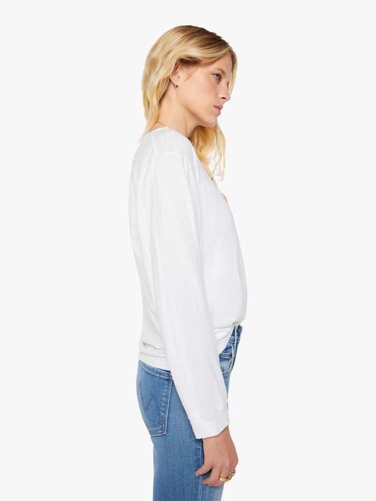 Side  view of a woman crewneck tee with long sleeves and an oversized fit in a bight white hue.