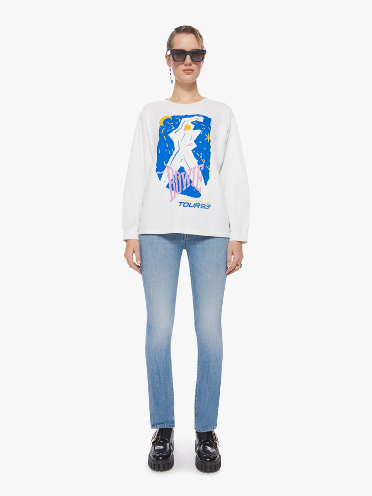 Full body view of a woman oversized long sleeve tee in white, the tee features a colorful graphic that channels the electrifying spirit of the tour.