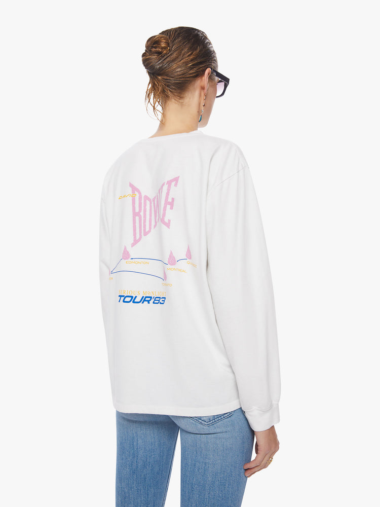 Back view of a woman oversized long sleeve tee in white, the tee features a colorful graphic that channels the electrifying spirit of the tour.