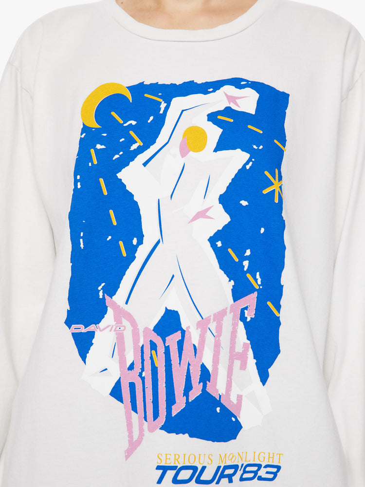 Close up view of a woman oversized long sleeve tee in white, the tee features a colorful graphic that channels the electrifying spirit of the tour.