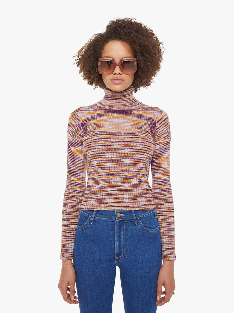 Front view of a woman in a graphic stripe print in orange, maroon and white  long sleeve knit top features a turtleneck and a narrow fit. 