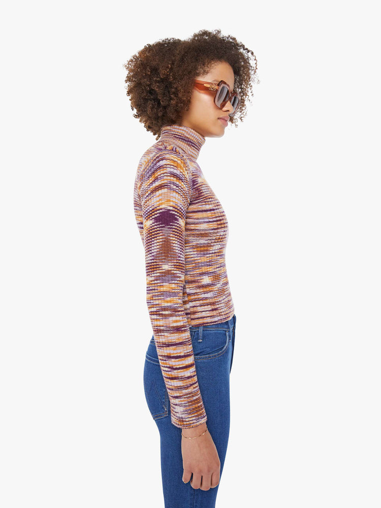 Side  view of a woman in a graphic stripe print in orange, maroon and white  long sleeve knit top features a turtleneck and a narrow fit. 