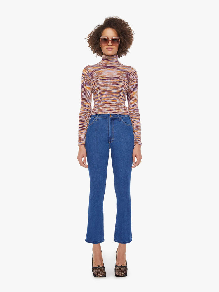 Full body  view of a woman in a graphic stripe print in orange, maroon and white  long sleeve knit top features a turtleneck and a narrow fit. 