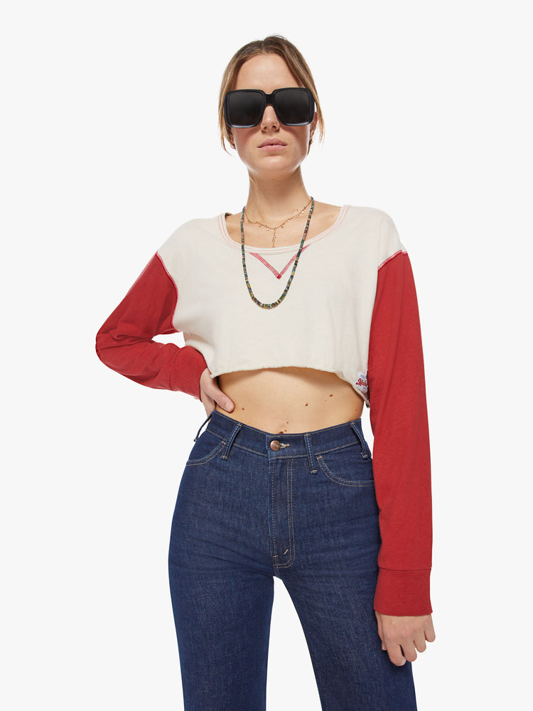 Front view of a woman longsleeve tee with a scoop neck, long sleeves, drop shoulders and a super-cropped hem in an off-white hue with red sleeves.