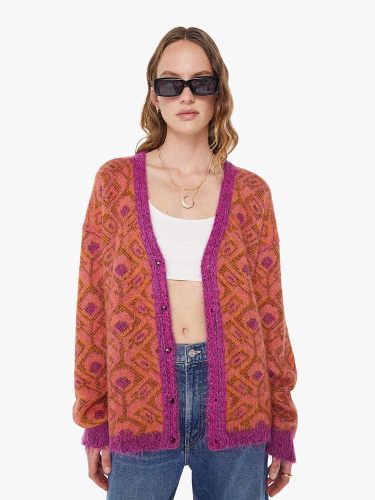Front view of a woman in a two equally bold sides in an orange, salmon and purple reversible oversized cardigan features a V-neck, drop shoulders, ribbed hems and buttons down the front.