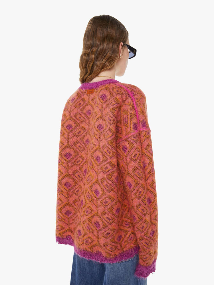 Back view of a woman in a two equally bold sides in an orange, salmon and purple reversible oversized cardigan features a V-neck, drop shoulders, ribbed hems and buttons down the front.