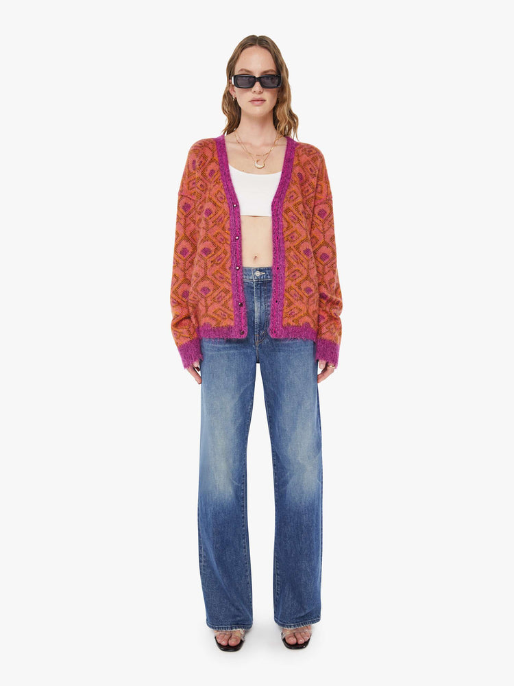 Full body view of a woman in a two equally bold sides in an orange, salmon and purple reversible oversized cardigan features a V-neck, drop shoulders, ribbed hems and buttons down the front.