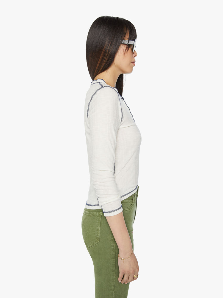 Side view of a woman with a buttoned crewneck, 3/4-length sleeves and a slightly shrunken fit in an sheer off white with black contrast stitch detailing.