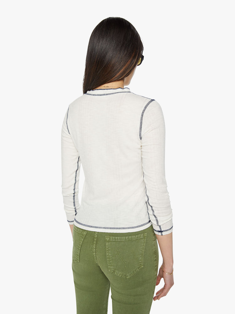 Back view of a woman with a buttoned crewneck, 3/4-length sleeves and a slightly shrunken fit in an sheer off white with black contrast stitch detailing.