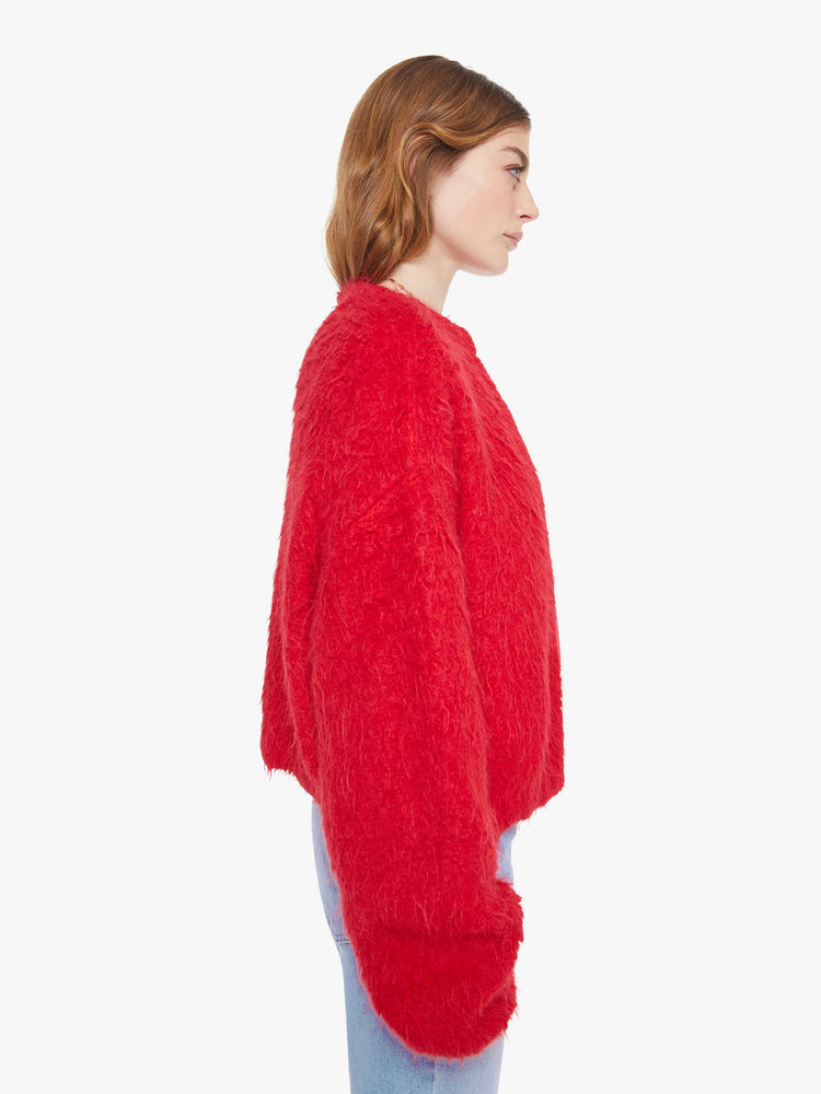 Side view of a woman in a red crewneck cardigan with drop shoulders, balloon sleeves and a slightly oversized fit. 